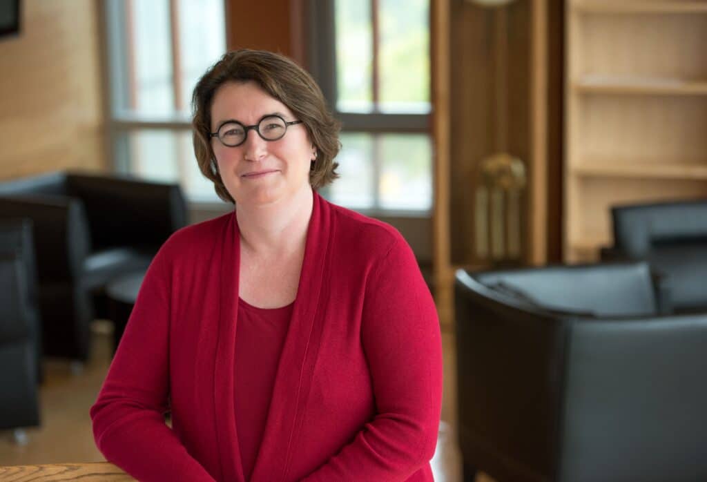 Cathy Shakespeare - woman with short brown hair and glasses wearing a pink shirt and cardigan