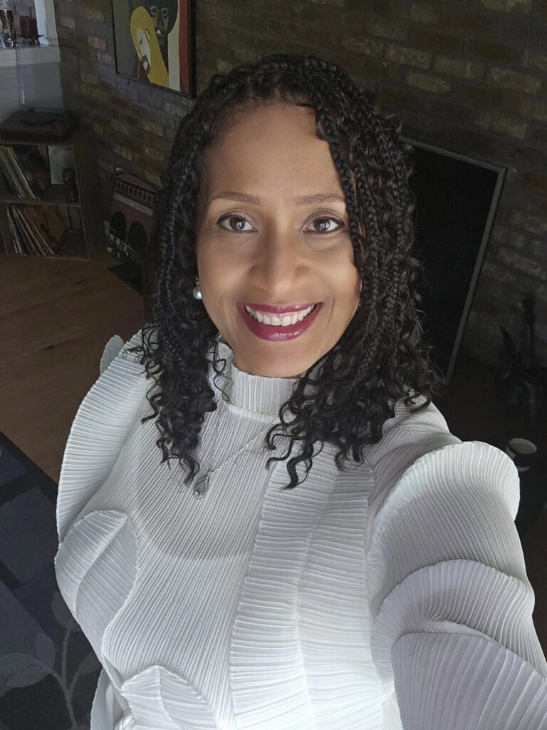 Diane Brinson-Days - a woman with dark, curly hair wearing a white sweater