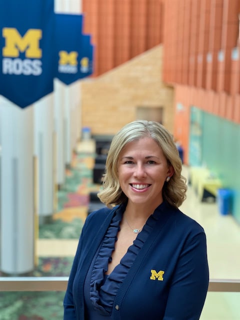 Jennifer Steben in the Winter Garden at Ross with Michigan Ross flags in the background