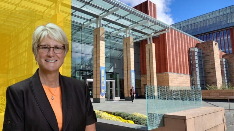 ross report cover photo - Kerry Flynn wearing a black blazer and orange shirt in front of a background image of the Michigan Ross building.
